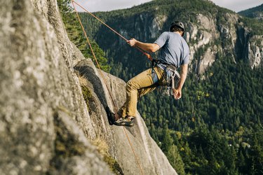 A rock climber gets lowered down a tall rock face on the end of a rope