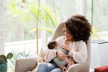 Mom breastfeeds newborn baby at home