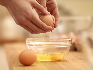 Cracking a raw egg into a mixing bowl