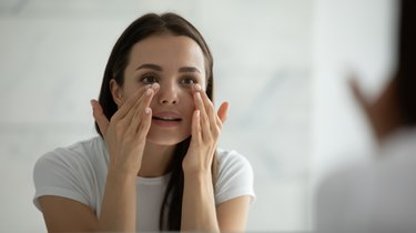 Close up smiling young woman doing facial massage, as a stye remedy