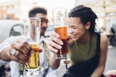 Happy young couple clinking beer glasses outdoors at a bar