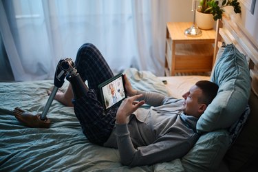Young man with prosthetic leg having online mental health session, as an example of affordable health care options