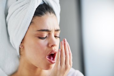 A woman checking her bad breath smell in the bathroom