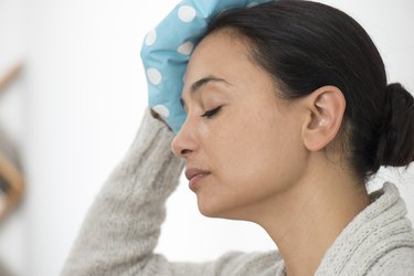 woman with cold compress on forehead, as a natural remedy for headaches