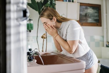 Woman in bathroom washing face, as a stye remedy