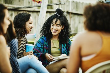 Smiling women sharing food and drinks during backyard barbecue