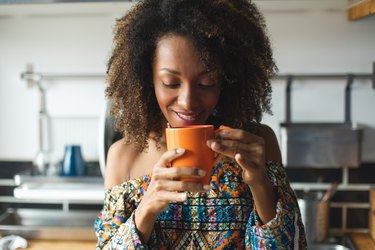 Woman drinking low-acid coffee from mug at home