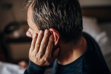 older man covering ear because of pulsatile tinnitus