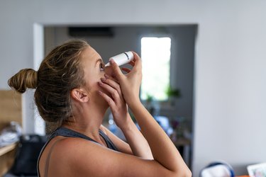 a side view of a person leaning back to put eye drops in their eye