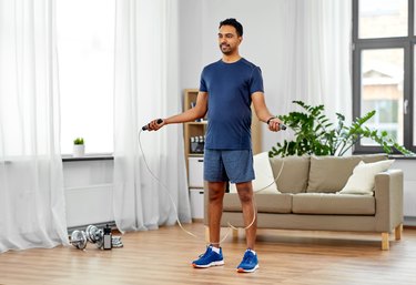Man exercising with homemade jump rope at home