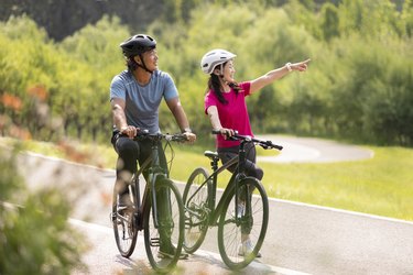 couple biking together on a trail in nature on best hybrid bikes