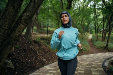 Person in activewear running outdoors through a park, creating mind-body trust to improve performance.