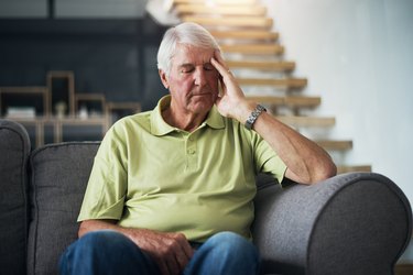 An older person sitting on the couch feeling tired because of low B12 levels