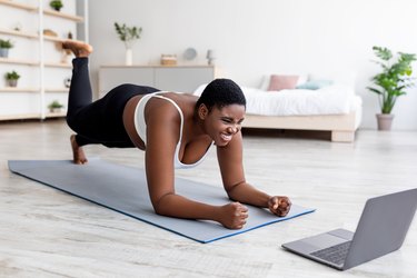 Plus size woman with osteoarthritis working out at home in elbow plank pose, as a way to modify exercise for osteoarthritis
