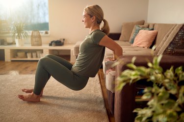 side view of a caucasian woman doing triceps dips with her hands on a couch