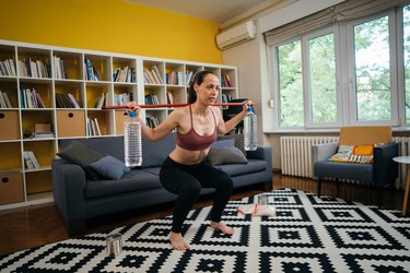 woman performing a squat with slosh pipe in living room