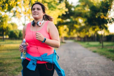 a woman in a pink top running outside with a water bottle, avoiding pre-run mistakes