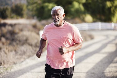 Close-up of older adult wearing a pink T-shirt running outside.