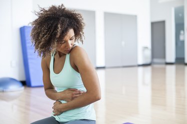 Woman at the Gym holding her side because she has liver pain during exercise