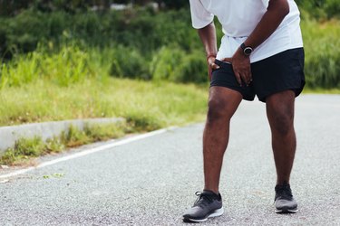 runner holding his leg in pain because of an inner thigh cramp