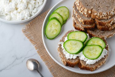 Slices of rye bread with cottage cheese and l-citrulline-rich cucumbers on white background"t"n