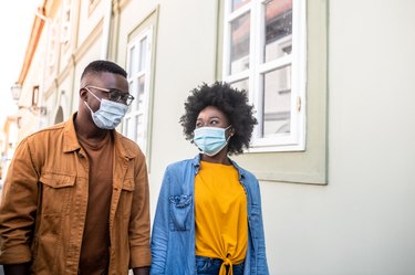 A young couple wearing masks on an outdoor date during COVID-19