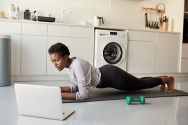 Woman performing plank exercise in her kitchen.