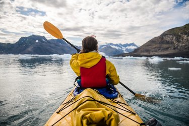 person paddling a kayak on an icy bay in Alaska exploring glaciers