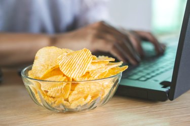 potato chips in bowl on office desk with blur background signifying relationship between salt and acid reflux