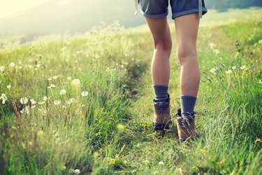 Young woman hiker walking on trail in meadow