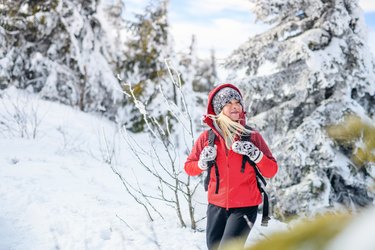 Portrait of senior woman hiking in snow covered winter forest, as an example of how to prevent winter weight gain