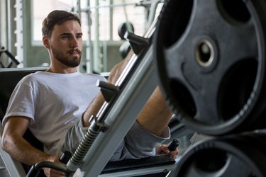 sport man doing exercises with leg press machine in fitness gym . workout . training