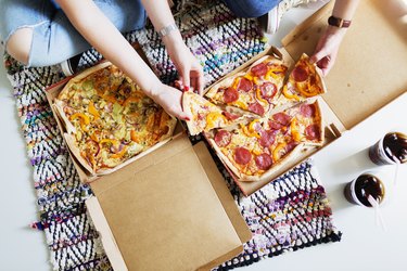 High angle view of friends eating pizza with cola in new home