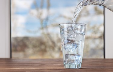 water pouring from jug into glass to relieve back and joint pain during fasting