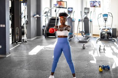 Person in the gym doing a kettlebell swing to demonstrate peripheral heart action training.