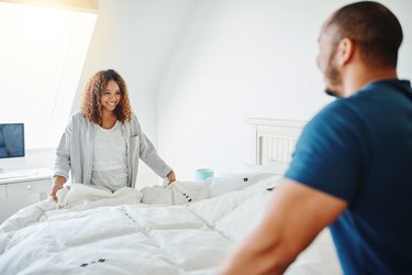 couple working together to make bed
