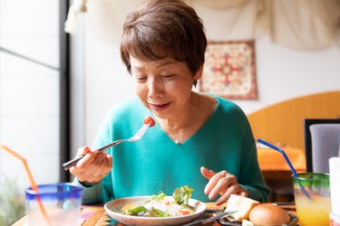 an older woman eating a salad, to represent how taste buds change as we age