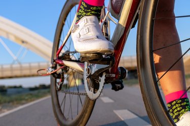 close up of white cycling shoes on a cycling riding a bike