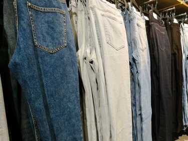Denim jeans hanging in a row in the clothing store to show how many clothes is 5 pounds