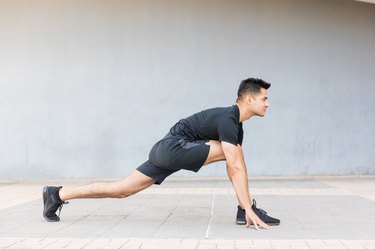 man in shorts stretching tight hamstrings