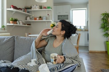 Woman drinking tea and using nasal spray, as a natural remedy for sinus infections