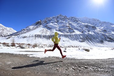 Woman trail runner cross country running  in winter mountains