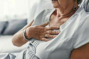 older woman with heartburn symptoms, with her hand on her chest from heartburn