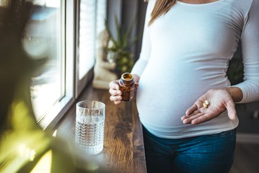 close view of a pregnant person taking prenatal vitamins that do not cause constipation