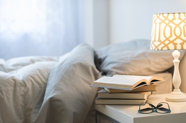 bed with lamp, books and glasses on bedside table