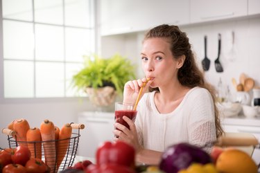 健康的年轻女人在厨房水果和蔬菜和果汁