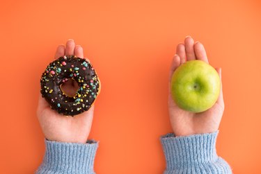 donut in one hand and apple in another hand