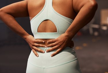 Shot of a woman experiencing back pain while working out in a gym