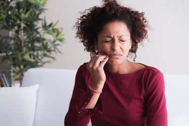 Black person touches their jaw in pain because the roof of their mouth is swollen