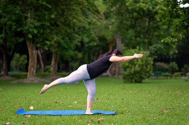 person practicing yoga and stretching on mat outside after IUD insertion